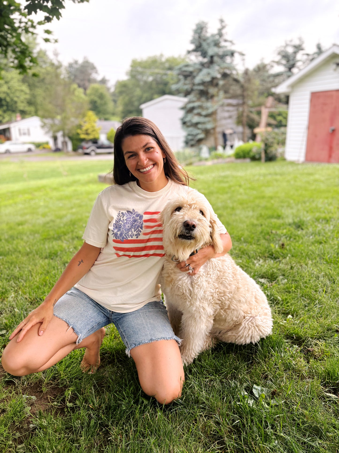 woman smiling with dog while wearing floral fourth of july shirt