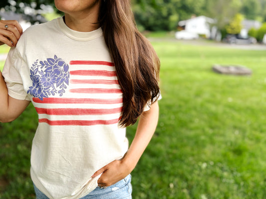 white graphic shirt with blue hand drawn flowers and red stripes