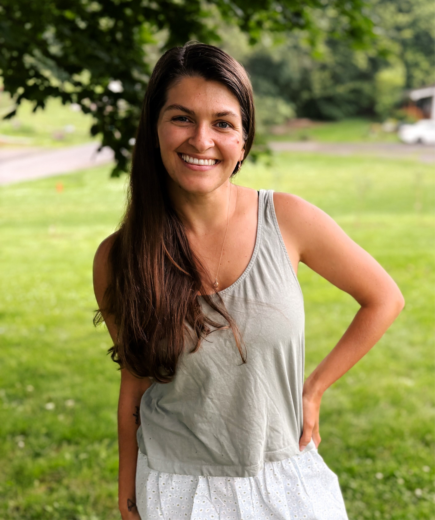 woman smiling at camera wearing mom crop tank in sage green