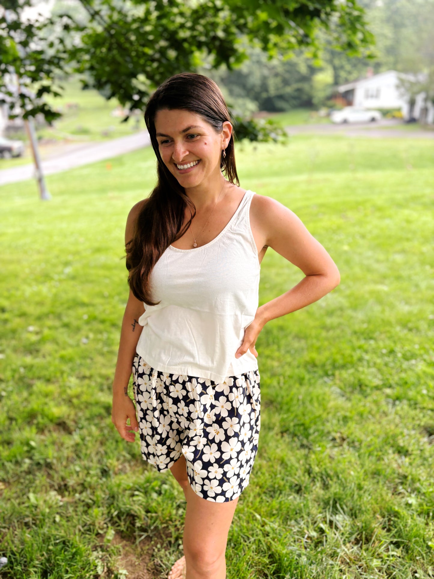 woman smiling wearing mom crop tank in white paired with blue and white floral shorts