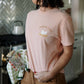 Person wearing a pink t-shirt with a chicken graphic and 'Fresh & Local' text in a kitchen.
