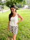 woman smiling wearing mom crop tank in white paired with blue and white floral shorts